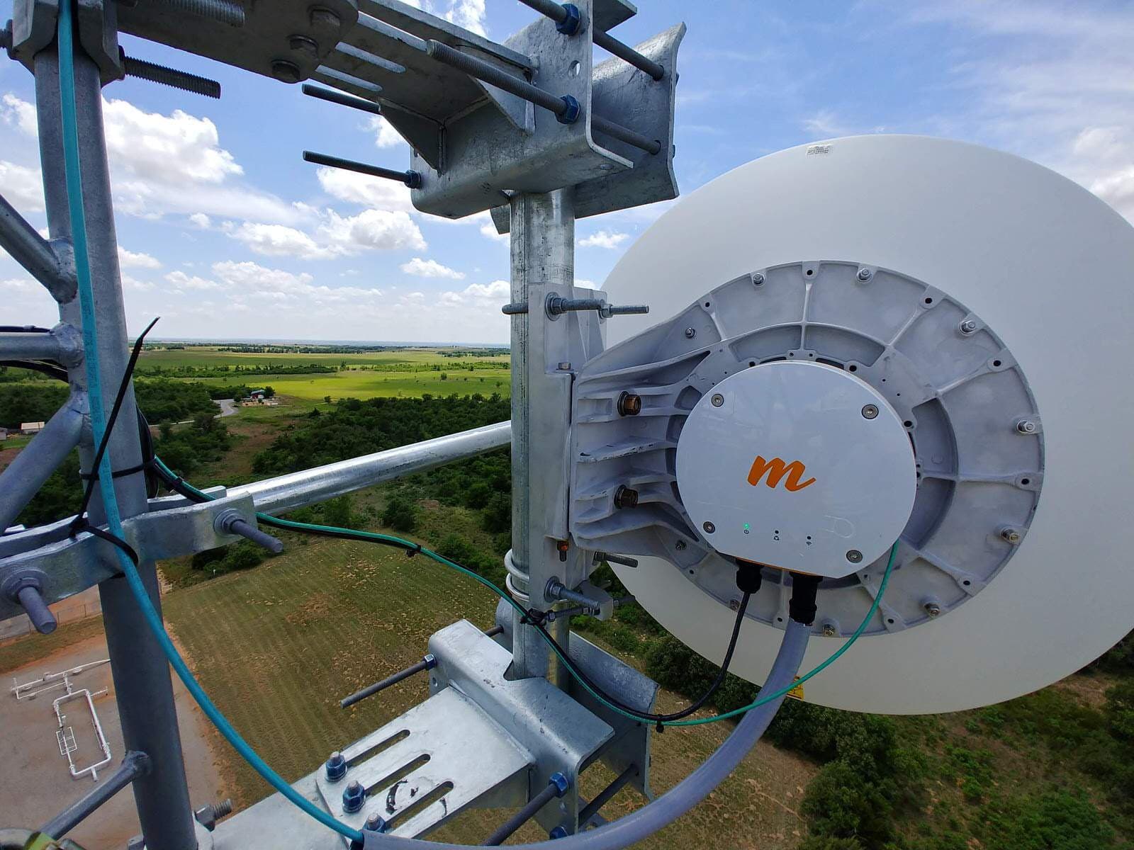 Microwave dish mounted on a communications tower overlooking farmland